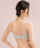 Woman wearing a light gray bra against a beige background