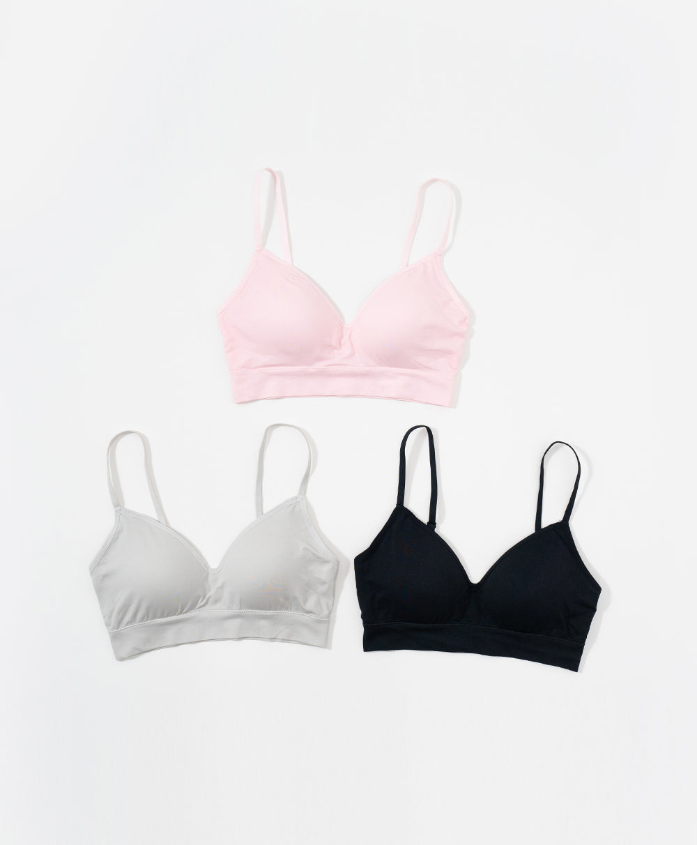 Three Sport bras in pink, white, and black on a light gray background