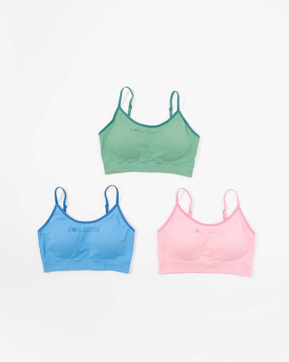 Three sports bras in green, blue, and pink .